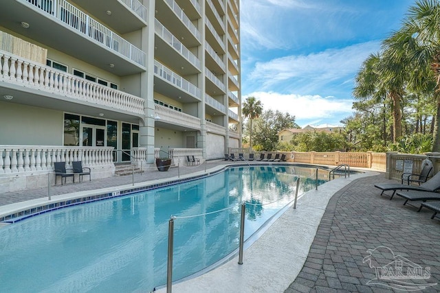 pool with a patio area and fence