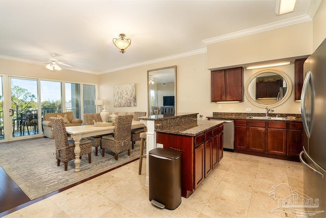 kitchen with stainless steel appliances, a sink, open floor plan, reddish brown cabinets, and dark stone countertops