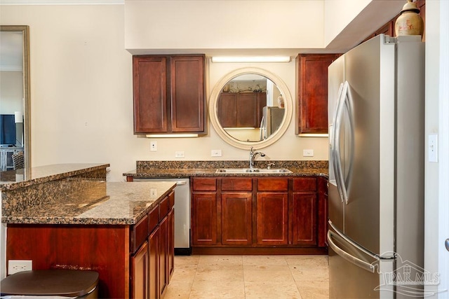 kitchen with dark stone counters, a center island, stainless steel appliances, dark brown cabinets, and a sink