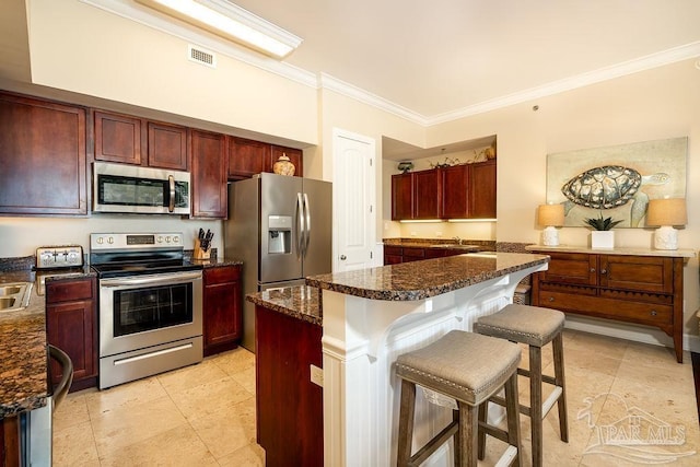 kitchen with stainless steel appliances, dark brown cabinets, visible vents, and a kitchen breakfast bar