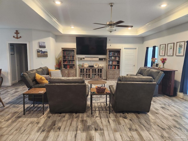 living room featuring a tray ceiling, ceiling fan, hardwood / wood-style floors, and ornamental molding