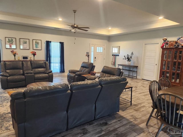 living room featuring ceiling fan, ornamental molding, and a tray ceiling