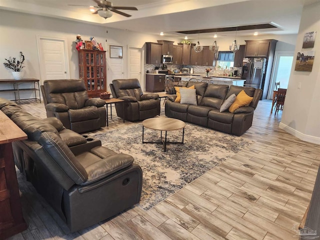 living room featuring ceiling fan and a tray ceiling