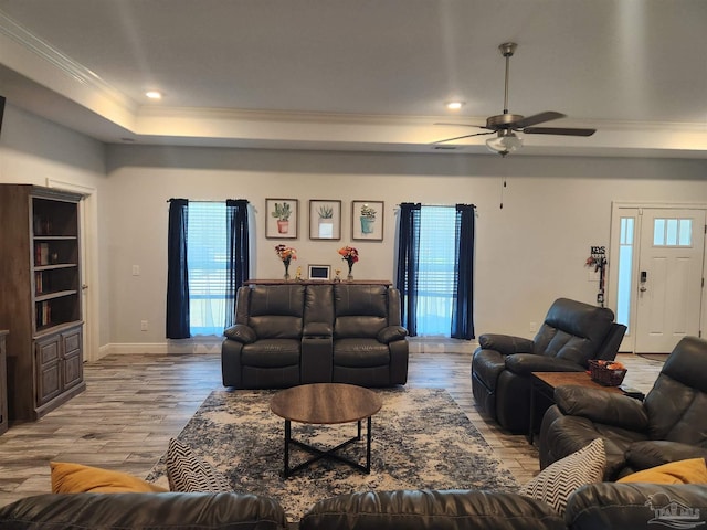 living room featuring a raised ceiling, ceiling fan, crown molding, and light hardwood / wood-style floors