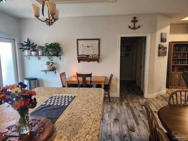 dining area with dark wood-type flooring and a notable chandelier