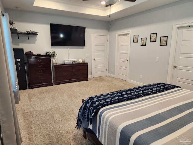 bedroom with ceiling fan, ornamental molding, light carpet, and a tray ceiling