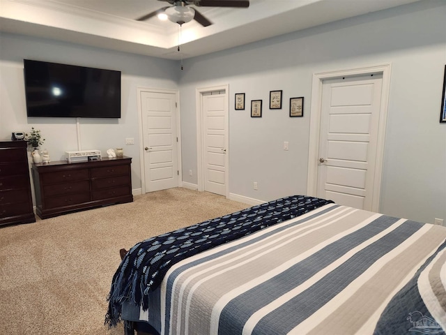 bedroom with carpet, ceiling fan, a raised ceiling, and ornamental molding