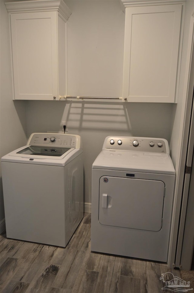 laundry room featuring dark hardwood / wood-style flooring, cabinets, and washing machine and clothes dryer