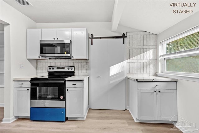 kitchen featuring decorative backsplash, stainless steel appliances, light countertops, light wood-type flooring, and white cabinetry