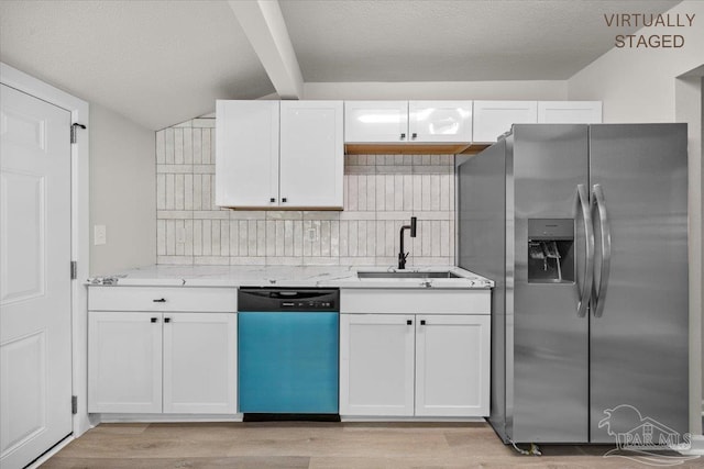 kitchen with appliances with stainless steel finishes, a sink, white cabinetry, and light stone countertops