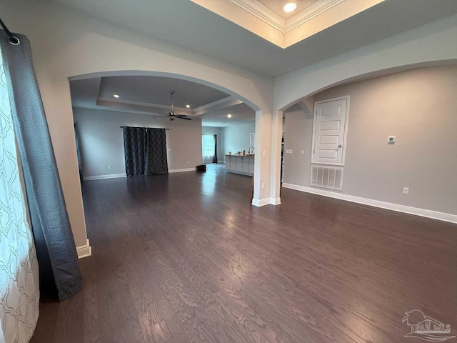 7912 Stream Ridge Rd, Pensacola, FL 32526 - unfurnished living room featuring a tray ceiling, crown molding, arched walkways, a ceiling fan, and dark wood-style flooring