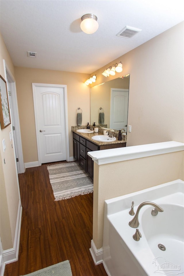 bathroom with a bathing tub, hardwood / wood-style floors, and vanity