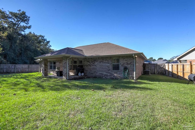 rear view of property featuring a yard and central AC