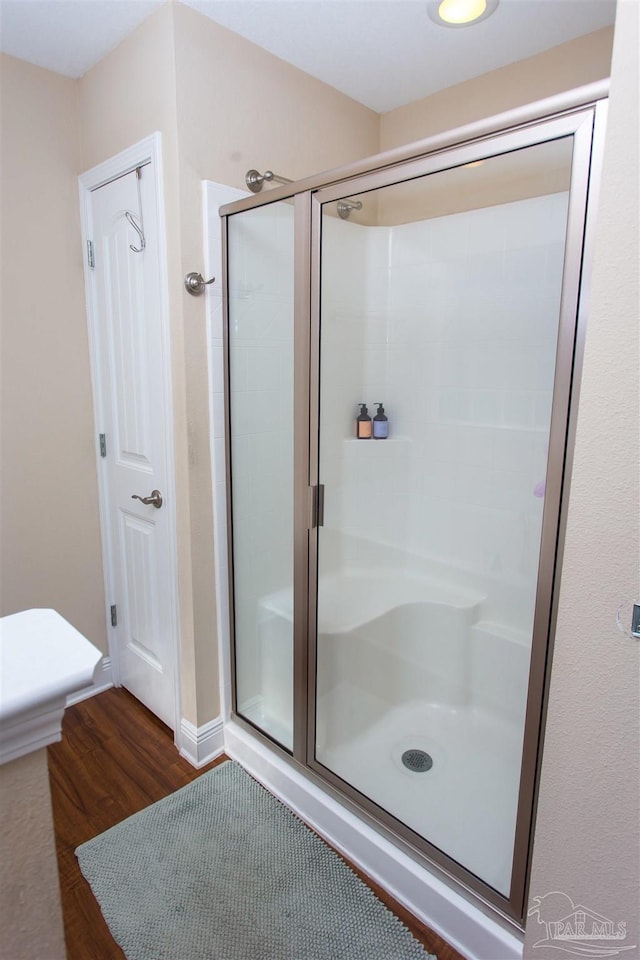 bathroom featuring a shower with shower door and wood-type flooring