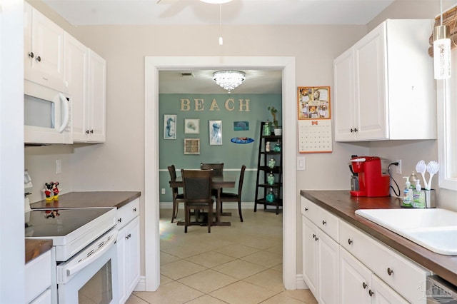 kitchen featuring sink, pendant lighting, light tile patterned floors, white cabinetry, and white appliances