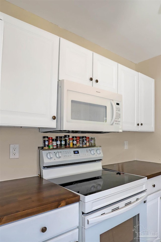 kitchen with white appliances, wood counters, and white cabinets