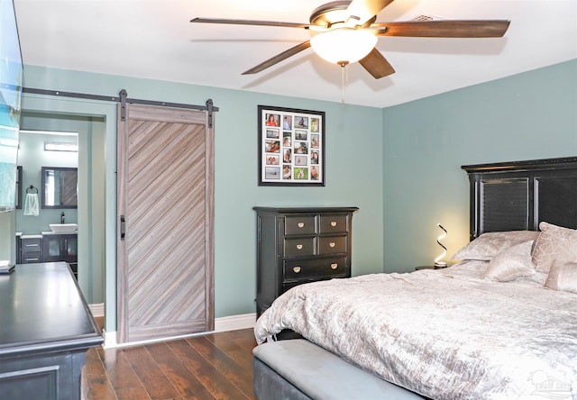 bedroom with connected bathroom, ceiling fan, dark hardwood / wood-style floors, and a barn door