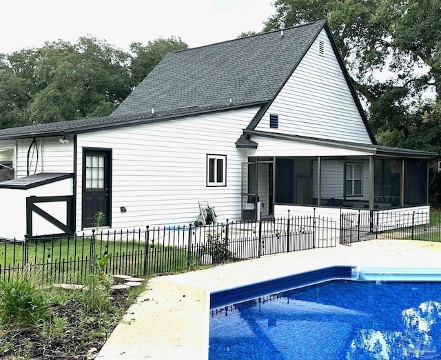 rear view of house with a sunroom and a fenced in pool