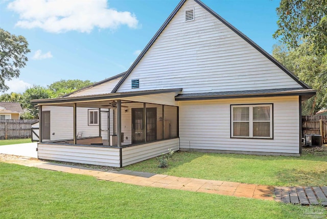 back of house with central AC, a sunroom, and a lawn