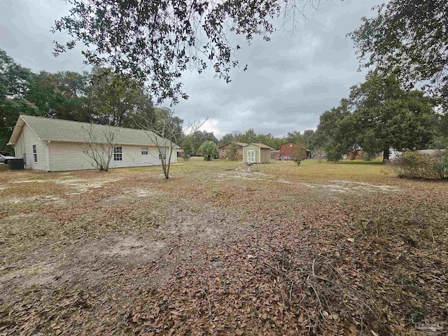 view of yard with central air condition unit and a storage unit