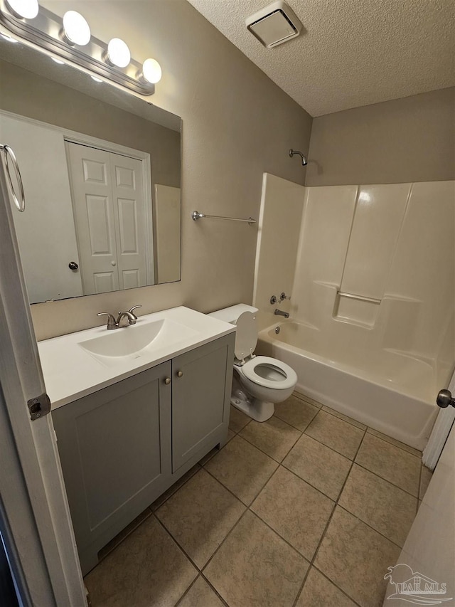 full bathroom featuring washtub / shower combination, vanity, a textured ceiling, tile patterned floors, and toilet