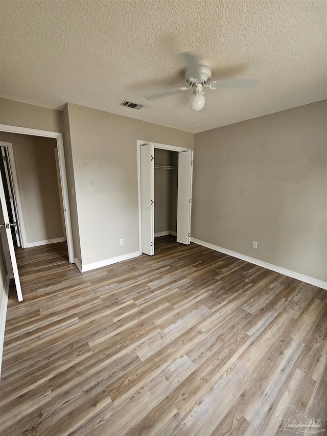 unfurnished bedroom with ceiling fan, a textured ceiling, light hardwood / wood-style floors, and a closet