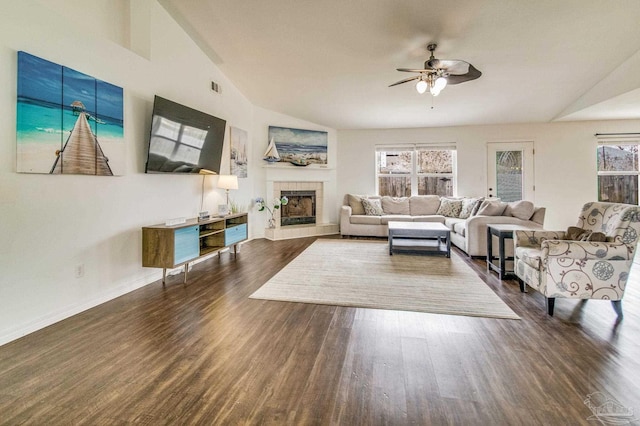 living room with lofted ceiling, a tiled fireplace, dark hardwood / wood-style floors, and ceiling fan