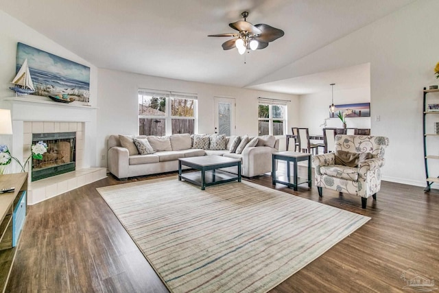 living room featuring lofted ceiling, a tiled fireplace, dark hardwood / wood-style flooring, and ceiling fan