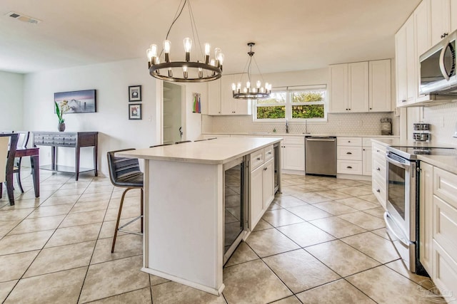 kitchen with white cabinetry, appliances with stainless steel finishes, a center island, and pendant lighting