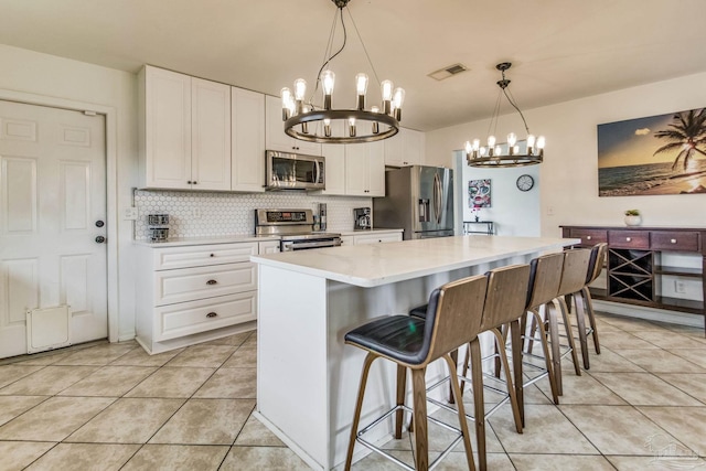 kitchen featuring stainless steel appliances, white cabinetry, a kitchen island, and pendant lighting