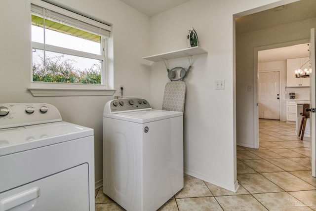 laundry area with an inviting chandelier, washer and dryer, and light tile patterned flooring