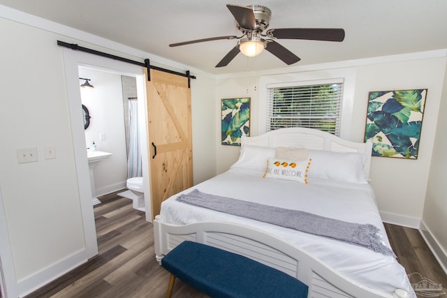 bedroom featuring a barn door, baseboards, and dark wood-style flooring