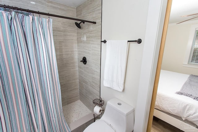 full bath featuring toilet, wood finished floors, and a tile shower