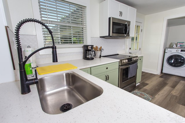 kitchen featuring washer / clothes dryer, tasteful backsplash, stainless steel appliances, green cabinets, and dark wood-style flooring