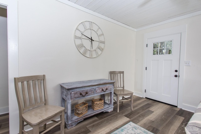 foyer entrance featuring baseboards, dark wood finished floors, wooden ceiling, and ornamental molding