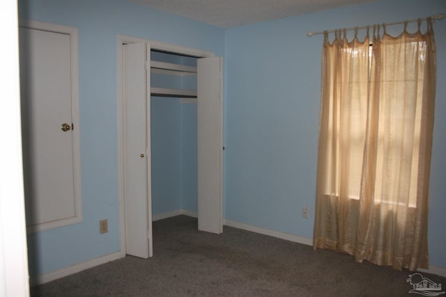 unfurnished bedroom with dark carpet and a closet