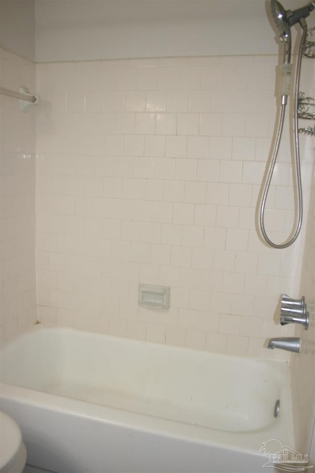 bathroom featuring toilet and tiled shower / bath