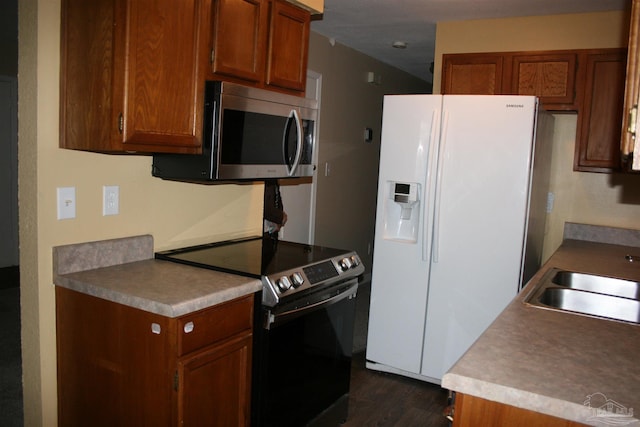 kitchen with appliances with stainless steel finishes, dark wood-type flooring, and sink