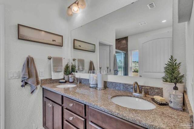 full bath with a shower stall, double vanity, a sink, and visible vents