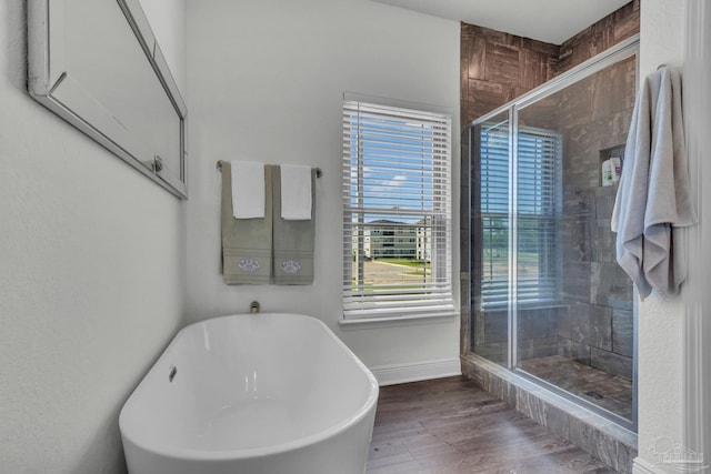 full bathroom with a stall shower, wood finished floors, baseboards, and a freestanding bath