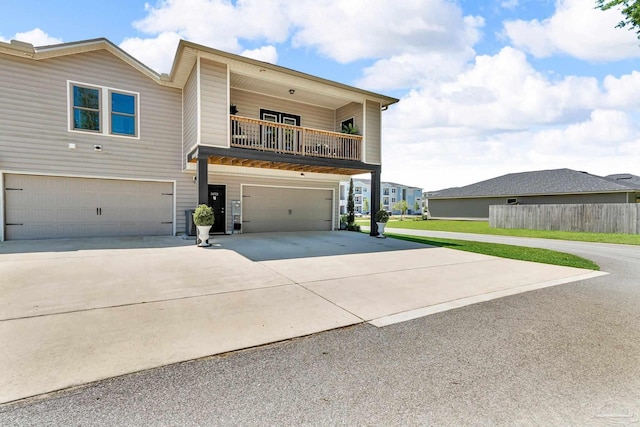 view of front of home featuring an attached garage, driveway, and a balcony
