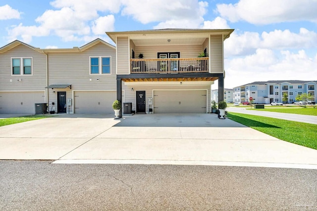 view of front of house with central AC unit, a balcony, a garage, and concrete driveway