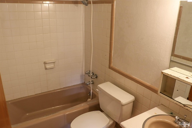 full bathroom with sink, tile walls, tiled shower / bath, decorative backsplash, and toilet