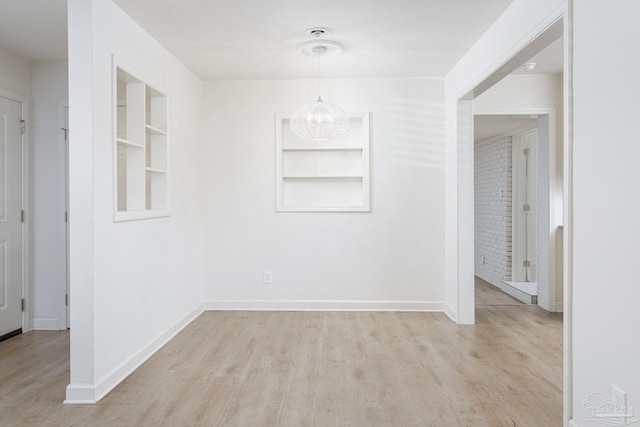 spare room featuring light hardwood / wood-style floors and a notable chandelier