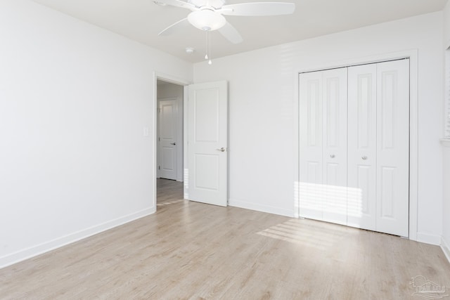 unfurnished bedroom featuring light wood-type flooring, ceiling fan, and a closet