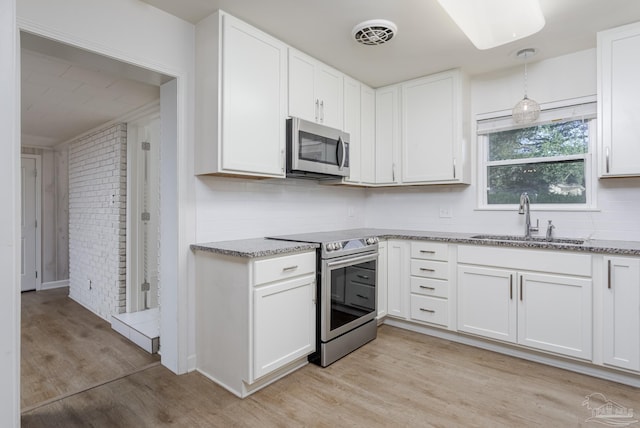 kitchen featuring white cabinetry, light wood-type flooring, stainless steel appliances, and sink