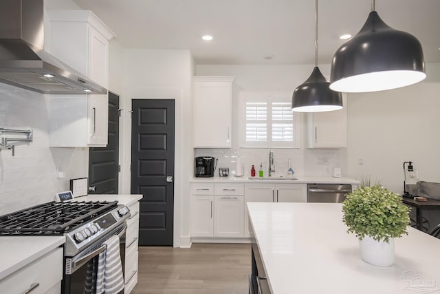 kitchen with white cabinets, stainless steel appliances, and wall chimney range hood