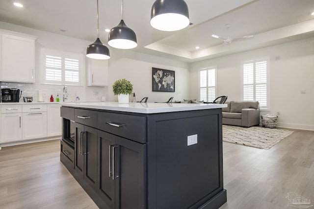 kitchen with decorative backsplash, light wood-type flooring, white cabinetry, and plenty of natural light