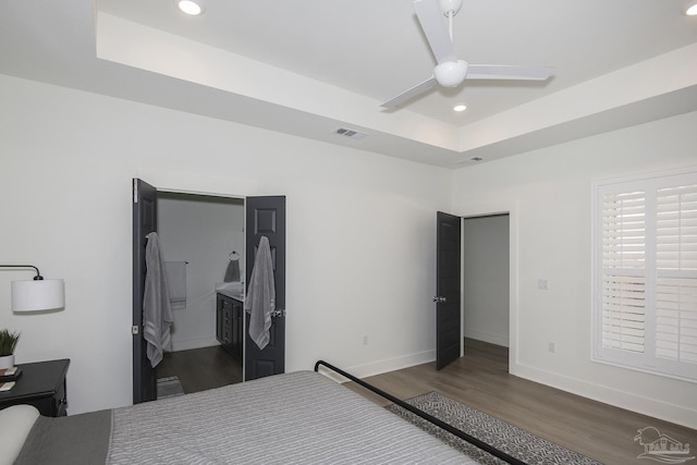 bedroom featuring ceiling fan, dark hardwood / wood-style floors, and a raised ceiling