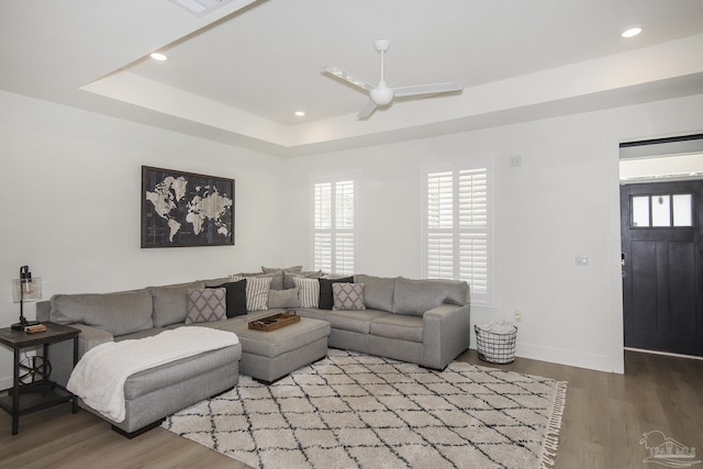 living room featuring a tray ceiling, ceiling fan, and light hardwood / wood-style floors